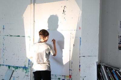 Kind zeichnet Schattenumriss an die Wand